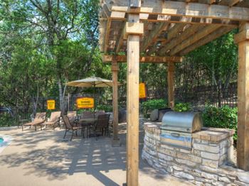 a patio with a wooden pergola and a bbq